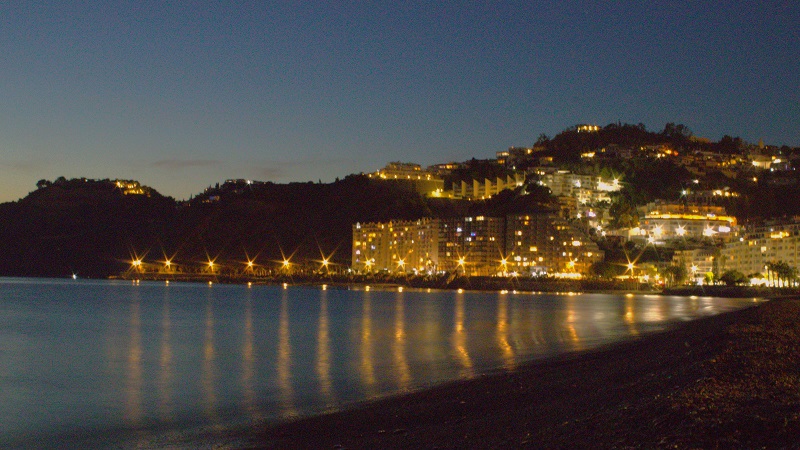 Almuñécar lyser upp natten med gyllene ljus längs stranden, speglat i det stilla Medelhavet.