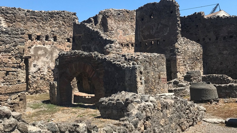 Pompeji Stenruiner i Pompeji med välbevarade valvbågar och väggar under klarblå himmel.