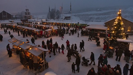 Julmarknad vid Falu Gruva. Foto: Per Eriksson Ett torg i skymning och julmarknad och gnistrande julgransljus.