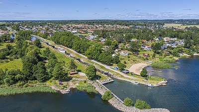 Bild: Visit Linköping & Co Foto: Fredrik Schlyter  Båt som åker genom slusstrappa med grön vacker miljö och vatten runt omkring.