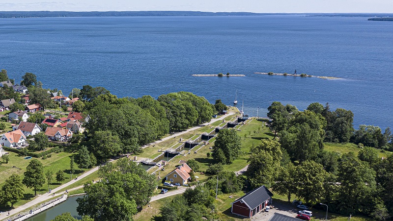 Bild: Visit Linköping & Co Foto: Fredrik Schlyter  Bild på båt som åker genom en sluss med fin grön miljö runt omkring och fint hav i bakgrunden