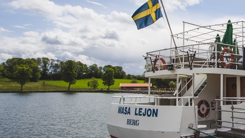 Bild: Visit Linköping & co Bild på baksidan av en båt med svensk flagga som vajar i vinden