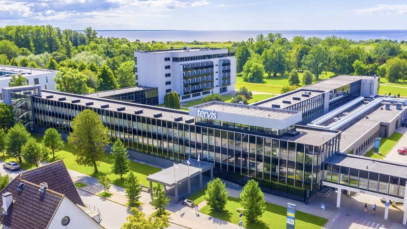 Flygfoto av modern hotellbyggnad omgiven av grönska, med skylten