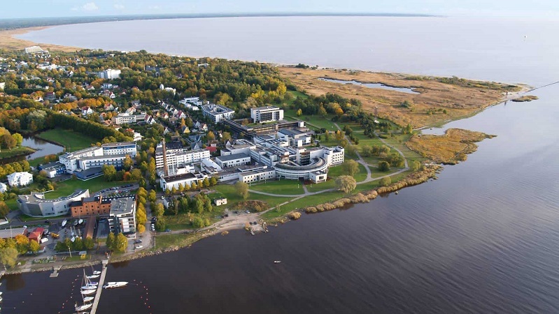 Flygfoto över kustnära stad med spa- och hotellområde, omgiven av grönska och vatten vid strandkanten.