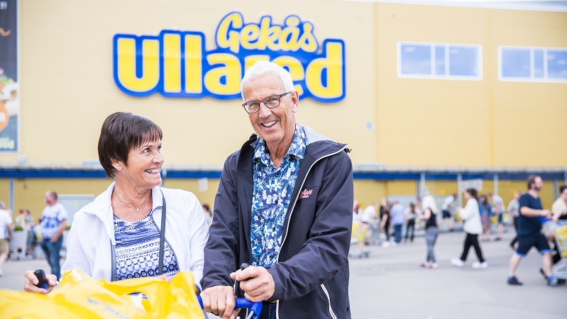 Ett leende äldre par med kundvagn utanför Gekås Ullared.